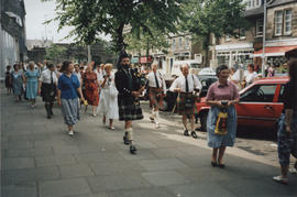 Photograph of people taking part in "Piping" in the Streets. Jim Rae leading, playing t...