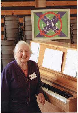 Photograph of Jean Sim, sitting at a piano