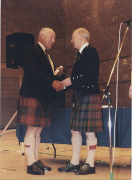 Photograph of Ian Hall receiving a scroll from Bill Clement