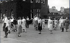 Photograph of a group dancing in mixed sets, taken outside