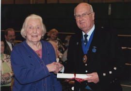 Photograph of Jean Sim  being presented with a Scroll by Alastair MacFadyen at the AGM, 2009