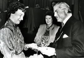 Photograph of Margaret MacWaters and Joan Moore receiving a scroll from Lord Mansfield at the AGM...