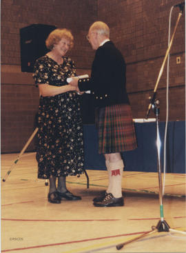 Photograph of Noreen MacLennon receiving a scroll from Bill Clement at the AGM, 1999